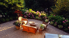 Pebble patio with outdoor furniture and flower gardens